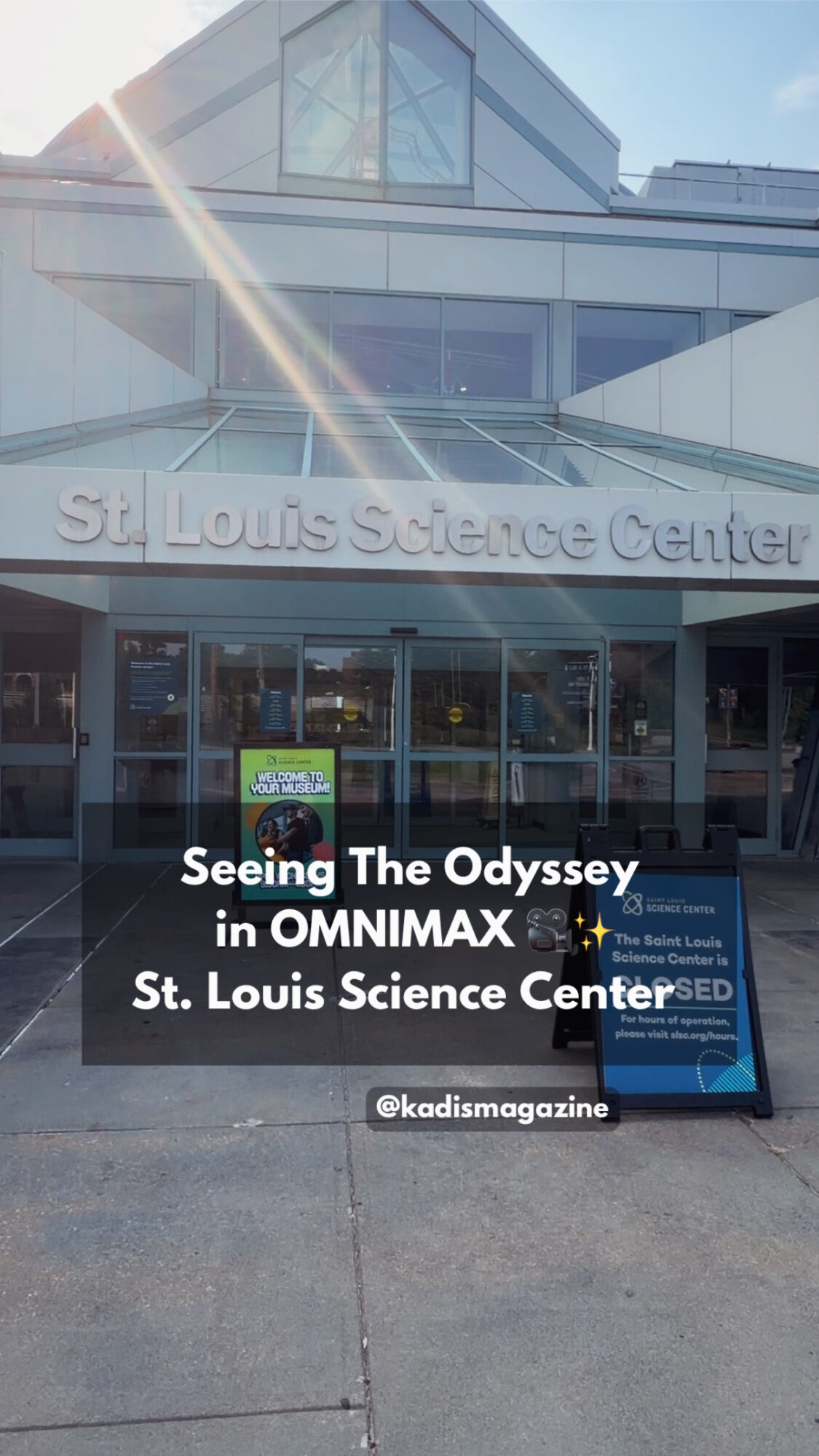 Entrance of St. Louis Science Center with signage and glass doors, sunny day, sidewalk in front.