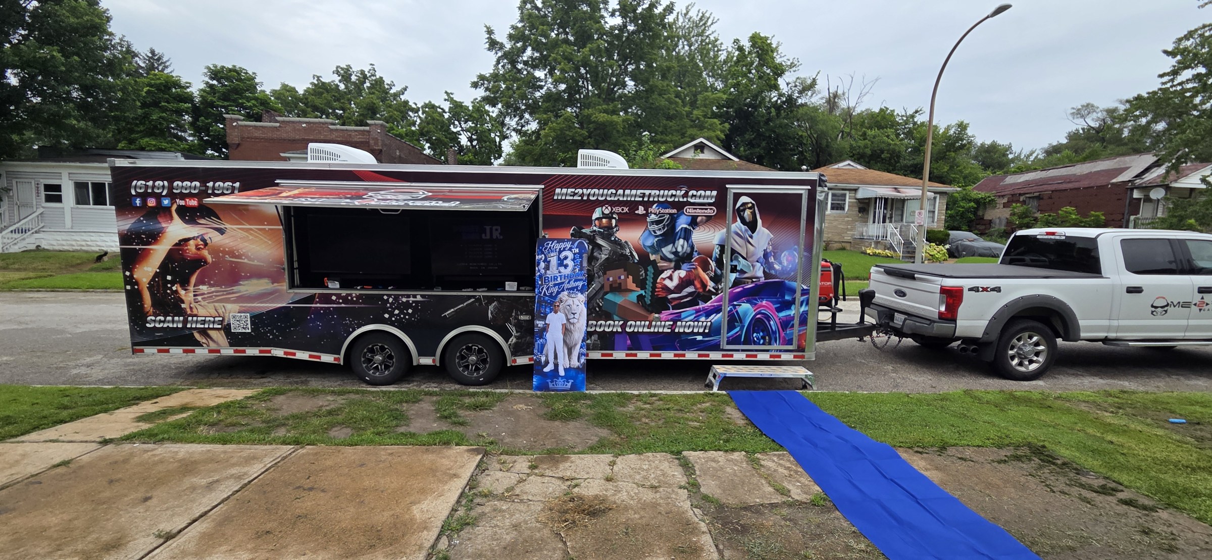 A large truck with a space-themed design is parked on a street, with a person in front and a blue carpet leading inside.