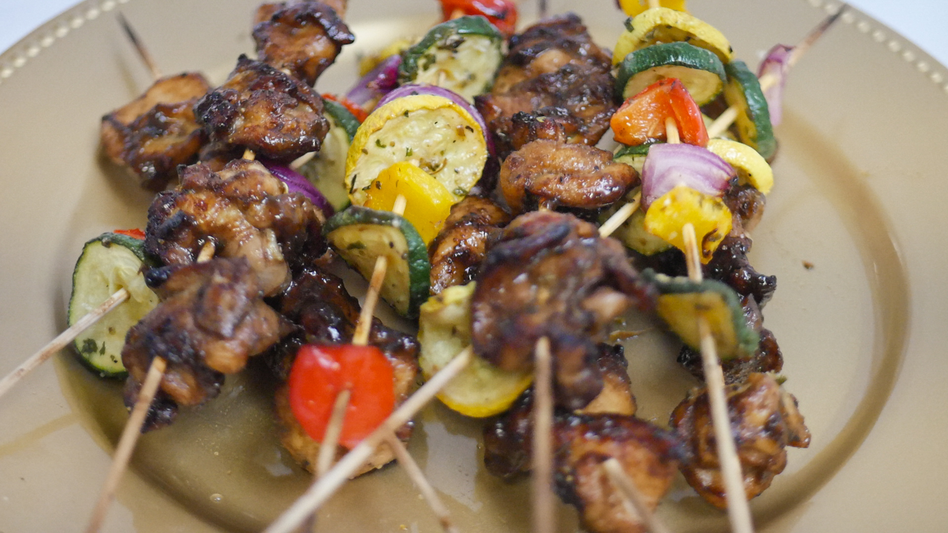 Skewers with grilled meat and colorful vegetables on a beige plate.