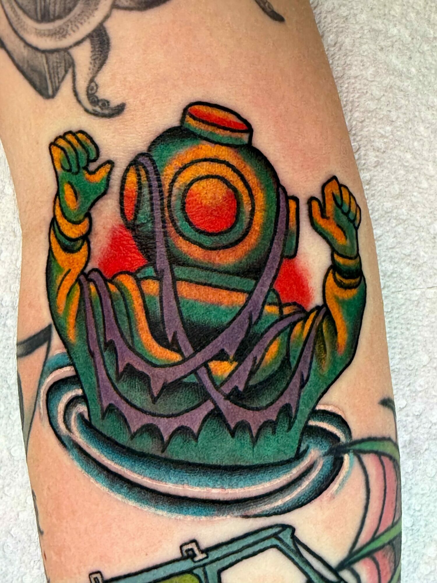 Colorful tattoo of a skull with orange, green, and purple hues on a person's arm.