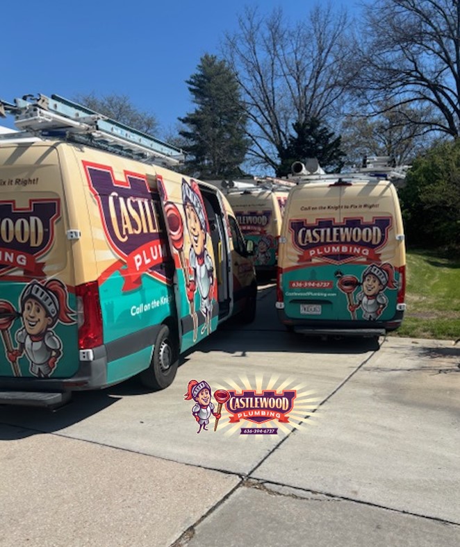 Two Castlewood Plumbing vans parked on a driveway with trees and blue sky in the background.