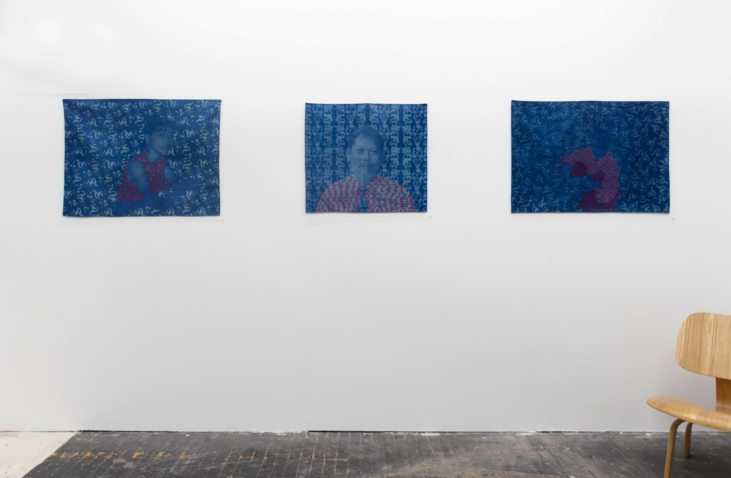 Three small framed images on a white wall, with a wooden chair partially visible on the right side.
