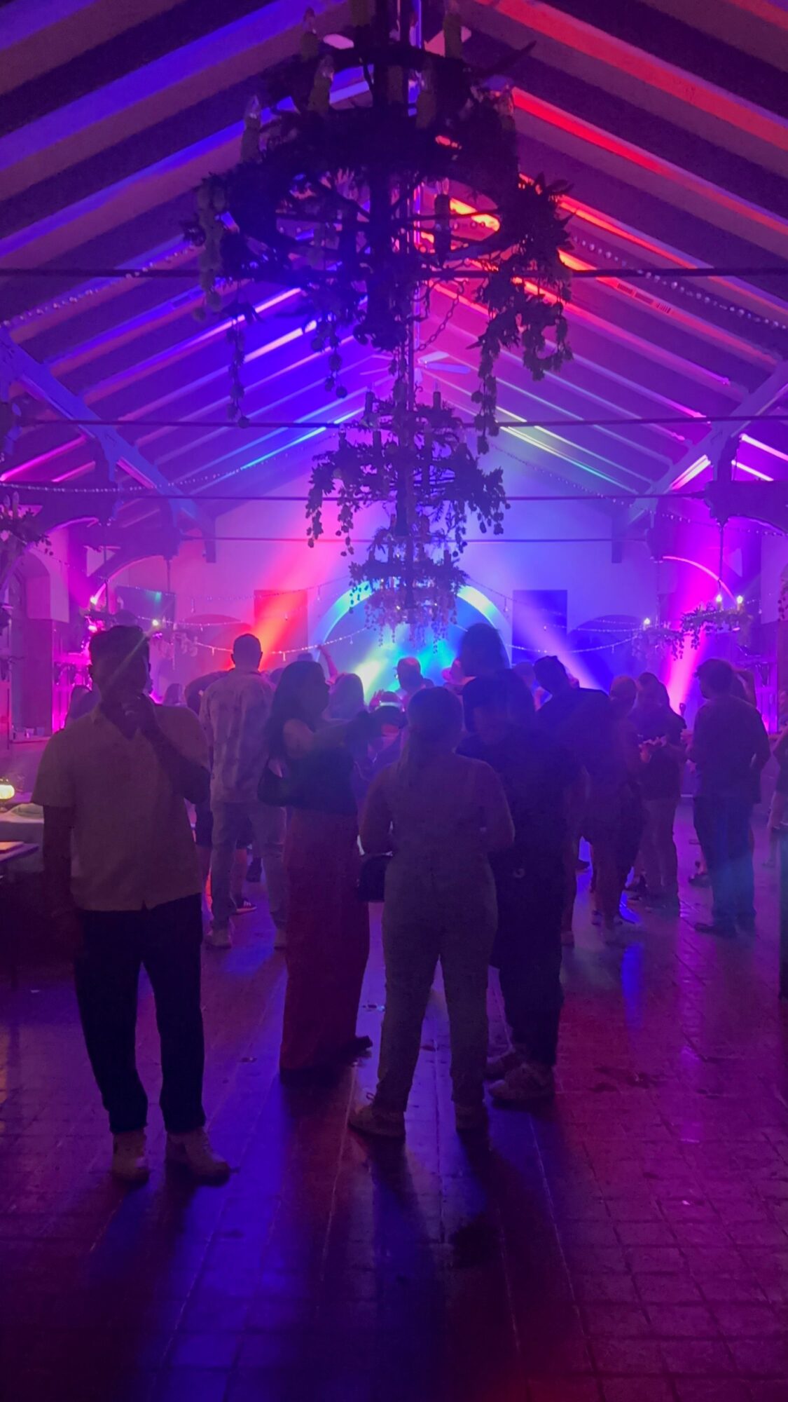 People dancing in a nightclub with colorful lights and a striped floor.
